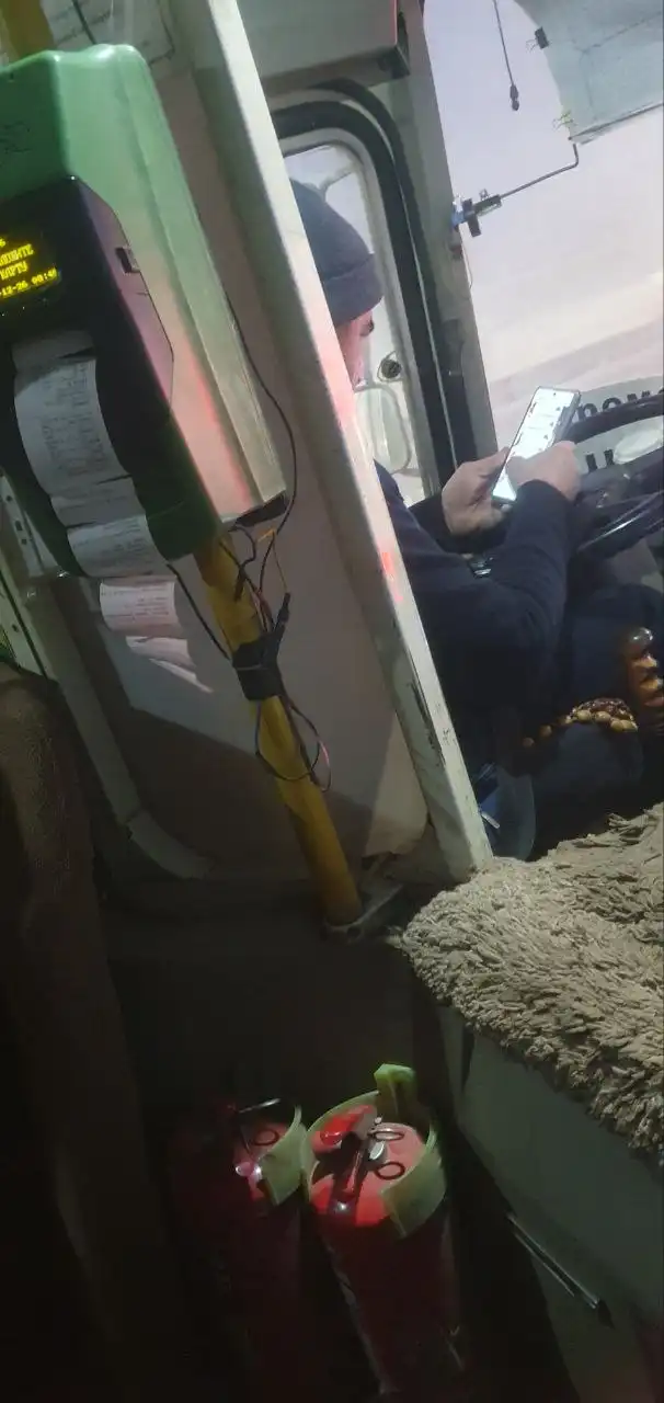 Водитель автобуса в телефоне во время движения